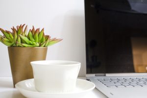 simple desk with laptop coffee and plant pot