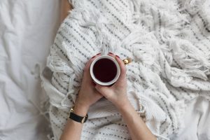 Soft photo of woman on the bed with the book and cup of tea in hands